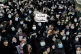 Mourners chant slogans as they hold a placard with Arabic th