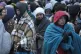Refugees wait in a crowd for transportation after fleeing fr