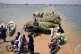 Victims of flooding from monsoon rains carry grasses for the