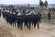 Police officers walk next to people who attend a protest ral