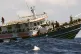 People on board a fishing boat wave as they are approached b