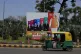 An auto rickshaw drives past a huge hoarding showing Indian 