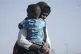 A Sudanese evacuee carries her son as they disembark from th