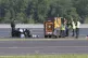 Police officers and security personnel stand on the airfield