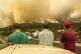 Local residents look on at a burning forest fire, near Punta