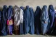 Afghan women wait to receive food rations distributed by a h