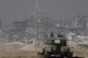 Israeli soldiers overlook the Gaza Strip from a tank, as see