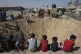 Palestinian children sit at the edge of a crater after an Is