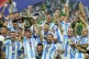 Argentina's Lionel Messi holds the trophy as celebrating wit