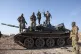 Syrian opposition fighters stand atop a seized military armo