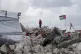 A man stands amid the rubble of homes, destroyed by the Isra