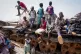 Children sit and play on the remains of a tank, at the river