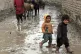 Afghan kids walk through a muddy street in Kabul 