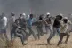 Palestinian protesters run to cover from Israeli troops alon