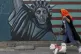 A woman walks her dog past a mural painted on the wall of th