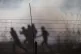 Palestinians protesters run from tear gas fired by Israeli t