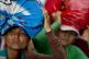 Farmers balance belongings on top of their heads as they wai