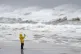 A person risks the winds to take a picture of the surf and f