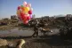An Afghan man walks with coloured balloons for sale on a mud