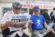 Two men read a local newspaper in Okinawa reporting on the r