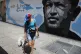 A woman walks her dog past a mural featuring Venezuela's lat