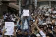 A Kashmiri Muslim boy holds a placard as others shout slogan