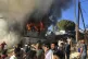 Migrants and refugees stand next to burning house containers
