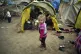 A child walks next to tends in a migrant camp set up near th