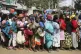 Women queue for a planned distribution of food for those suf