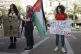 Protesters hold signs and Palestinian flag during a rally ag