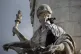 A demonstrator clenches her fist as she stands on a statue o