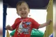 Alan Kurdi, a toddler, smiling in a playground 
