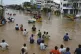 People wade through a flooded road after heavy rains in Vija