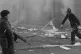 A soldier stands by as a firefighter fights a blaze after 14