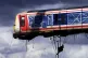 A crane lifts the train carriage over the roof from where it