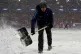 Ground staff shovel snow off the pitch during the Emirates F