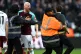 A pitch invader is confronted by security during the Premier