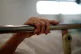 The hand of a patient grips the rail of a hospital bed in th