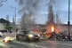 A car drives past the wreckage of a Translink Metrobus on fi