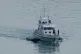 Royal Navy HMS Blazer tows two small boats as it arrives in 