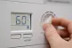 A homeowner turning down the temperature of a gas boiler
