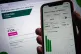 The OVO Energy app on a mobile phone is held against a lapto