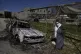 A Palestinian stands beside a torched car in the aftermath o
