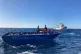 Members of the Open Arms crew stand on a wooden boat in the 