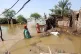 Women wade through a flooded area after heavy rains in the S